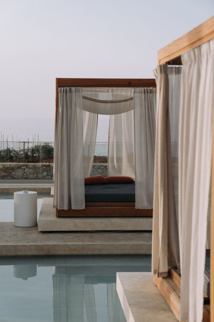 Elegant outdoor canopy bed by a serene poolside, offering luxury and relaxation.