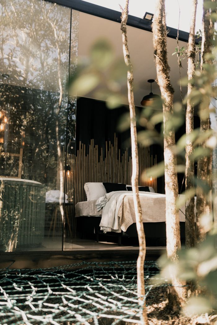 About Serene glass wall bedroom in a forest cabin, perfect retreat.