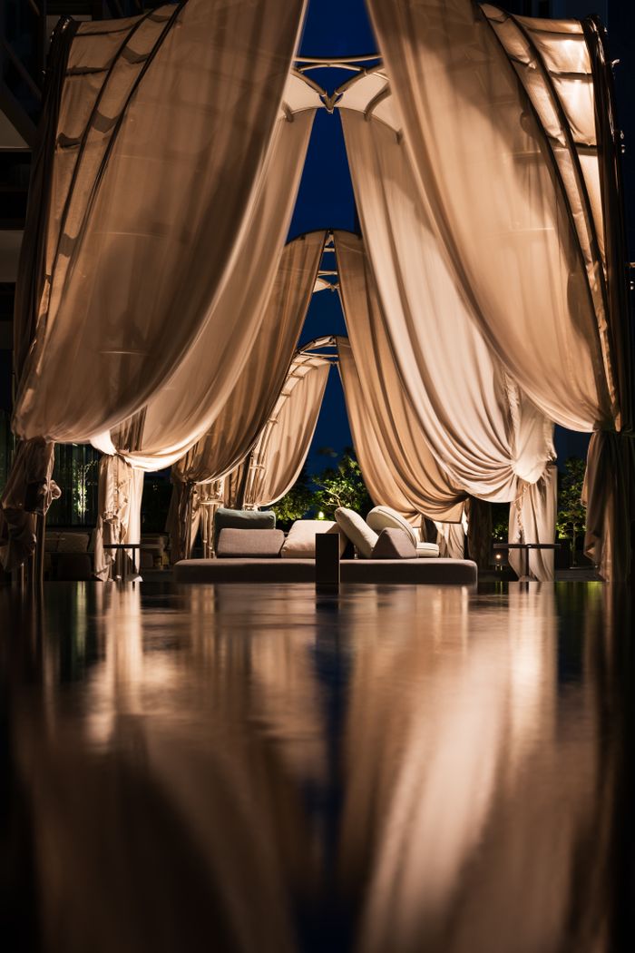 Elegant cabana with flowing curtains and ambient lighting, creating a serene nighttime atmosphere in Singapore.
