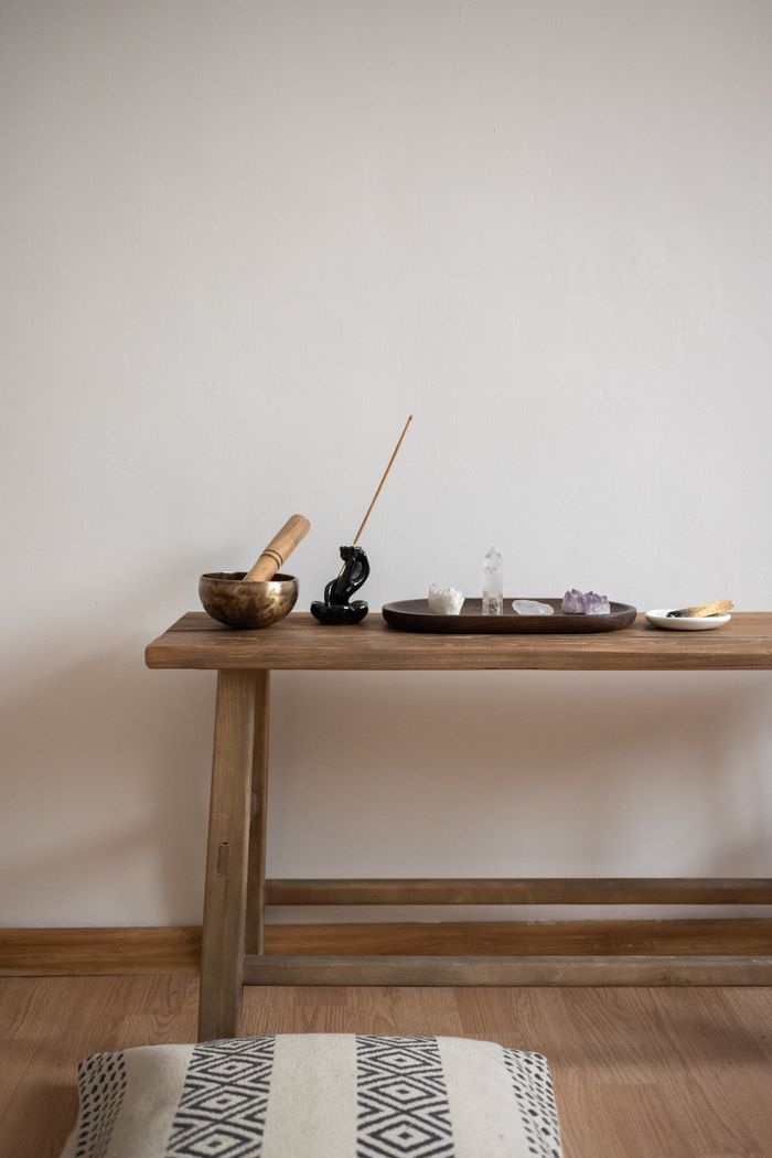 Peaceful table setup featuring incense, crystals, and a bowl on a wooden table.